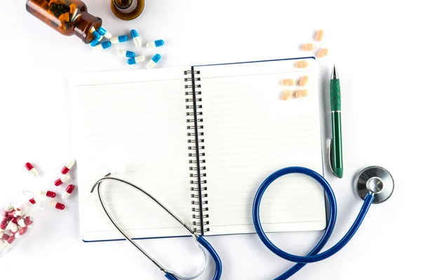 Capsules and bottle with notebook and pen and stethoscope — Stock Photo, Image