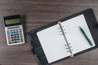 defter ve kalem masanın üzerinde hesap makinesi ile
