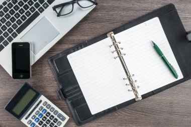 Cep telefonu defter ve kalem masanın üzerinde hesap makinesi ile