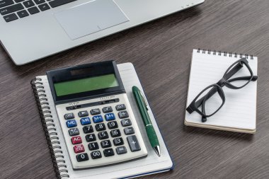 laptop, defter ve kalem masanın üzerinde hesap makinesi ile