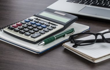 laptop, defter ve kalem masanın üzerinde hesap makinesi ile