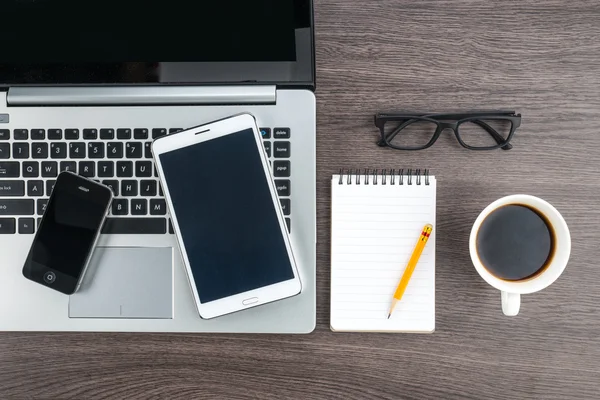 Dizüstü bilgisayar cep telefonu ve masanın üstünde defter ile Tablet 