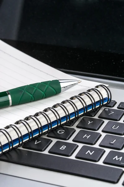 Notebook e caneta no teclado do laptop, de perto — Fotografia de Stock