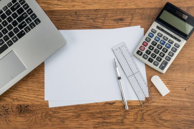 Dizüstü bilgisayar, kağıt kalem cetvel hesap makinesi ve çalışma masası üzerinde silgi