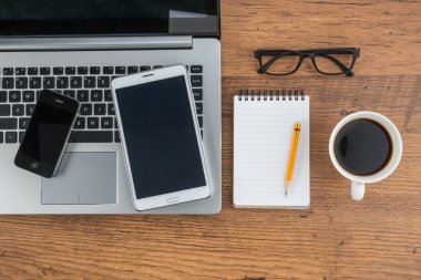 Dizüstü bilgisayar cep telefonu ve masanın üstünde defter ile Tablet 