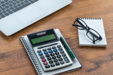 laptop, defter ve kalem masanın üzerinde hesap makinesi ile