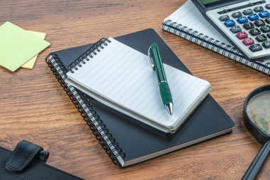 defter, kalem ve masanın üstüne hesap makinesiyle Büyüteç