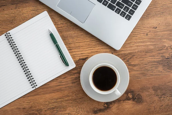 Laptop, notebook e xícara de café na mesa de trabalho — Fotografia de Stock