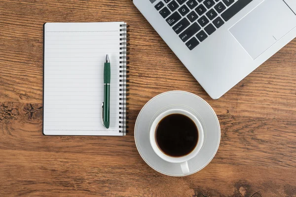Laptop, notebook e xícara de café na mesa de trabalho — Fotografia de Stock