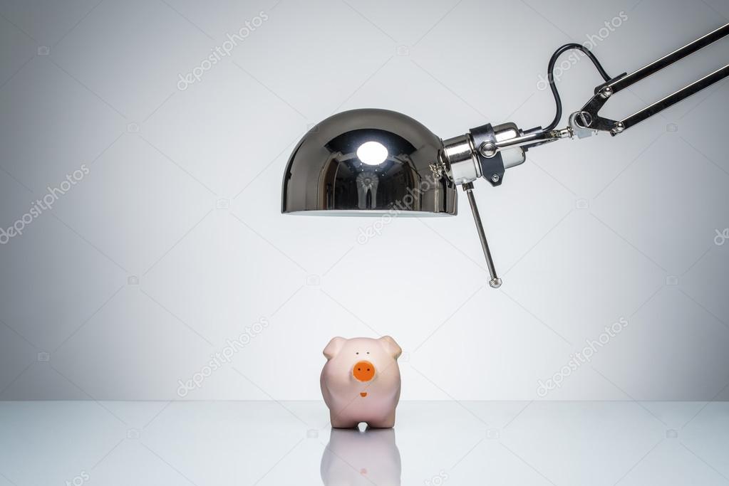 lighting up pink piggy bank with desk lamp