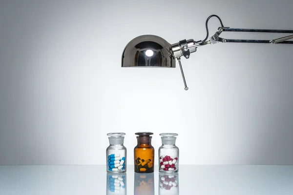 Medikamente mit Schreibtischlampe aufleuchten — Stockfoto