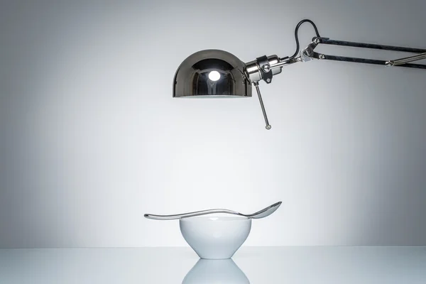 화이트 세라믹 그릇은 숟가락을 책상 램프와 조명 — 스톡 사진