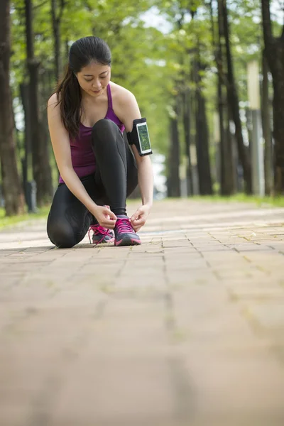 Азиатская молодая бегунья завязывающая шнурки здоровый образ жизни — стоковое фото