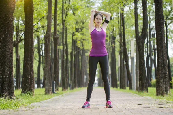 Sportif genç Asyalı kadın ormanda koşu sonra germe