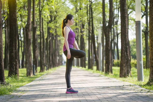 Sporty giovane donna asiatica stretching dopo jogging nella foresta — Foto Stock