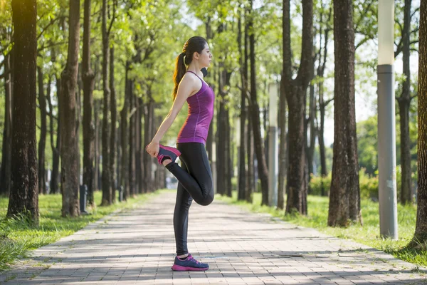 Desportivo jovem asiático mulher alongamento depois de correr na floresta — Fotografia de Stock