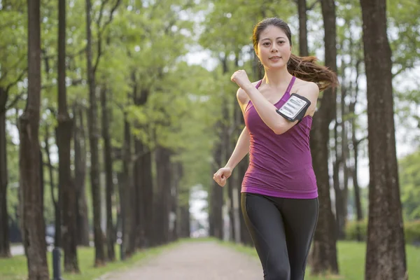 Aziatische jonge vrouw joggen in het forest, mobiele telefoon — Stockfoto