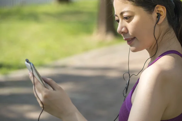 Deportiva asiática mujer escuchando música después de trotar en el bosque Fotos De Stock Sin Royalties Gratis