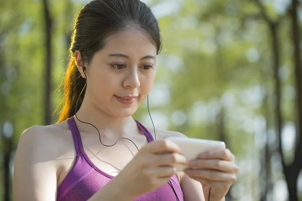 Deportiva asiática mujer escuchando música después de trotar en el bosque Imagen De Stock