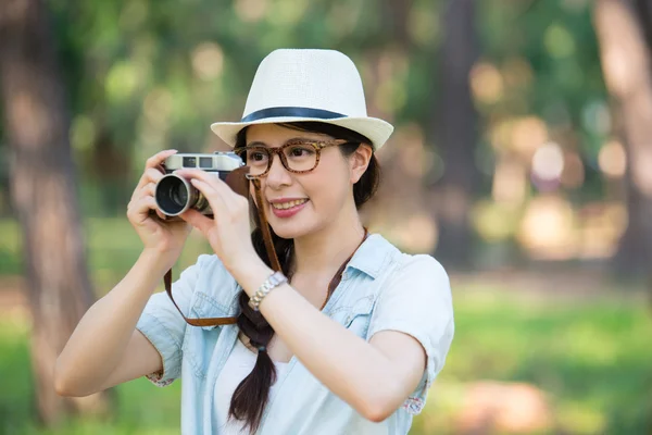 Schöne junge Mädchen lächelt mit Retro-Kamera fotografieren, ou — Stockfoto