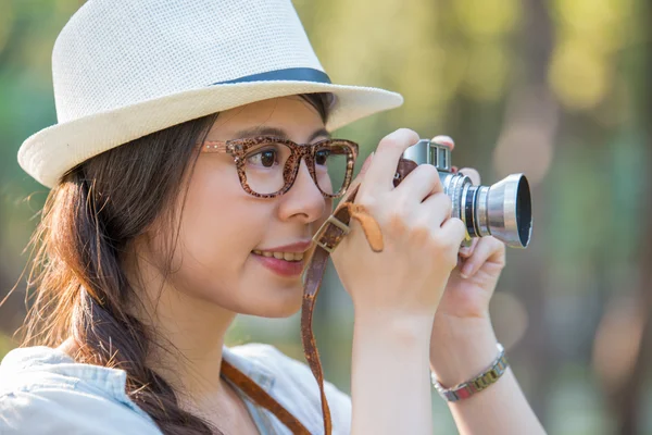 Schöne junge Mädchen lächelt mit Retro-Kamera fotografieren, ou — Stockfoto