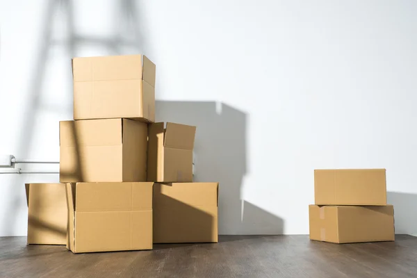 Montón de cajas de cartón sobre fondo blanco con sombra de escalera — Foto de Stock