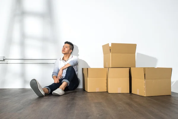 Un uomo asiatico yong seduto sul pavimento con scatole — Foto Stock