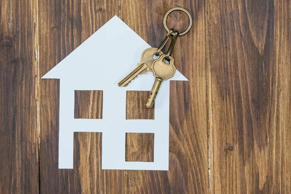 Casa con llave sobre fondo de madera, casa nueva —  Fotos de Stock