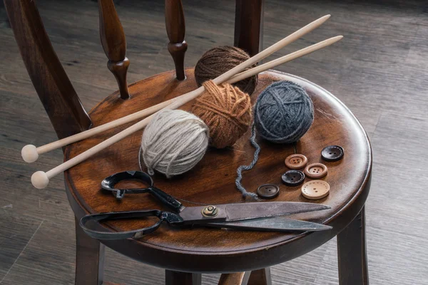 Bouton, ciseaux et boule de fil sur chaise en bois — Photo