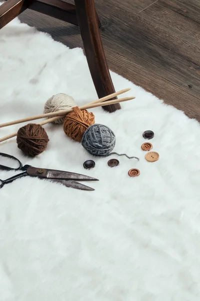 Bottone, forbici e palla di filato su tappeto — Foto Stock