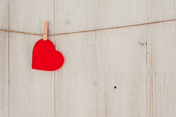 Red heart hanging on the clothesline. On old wood background — Stock Photo, Image