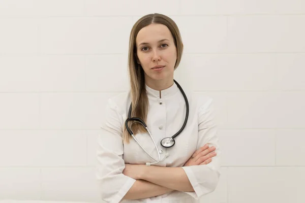 Smiling doctor with crossed arms with stethoscope on white background.