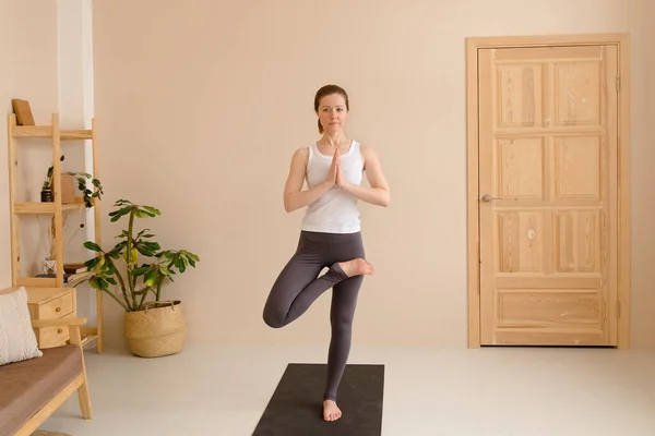 Spor elbiseli hoş bir kadın evde dinlenirken yoga yapıyor, sağlık konsepti.