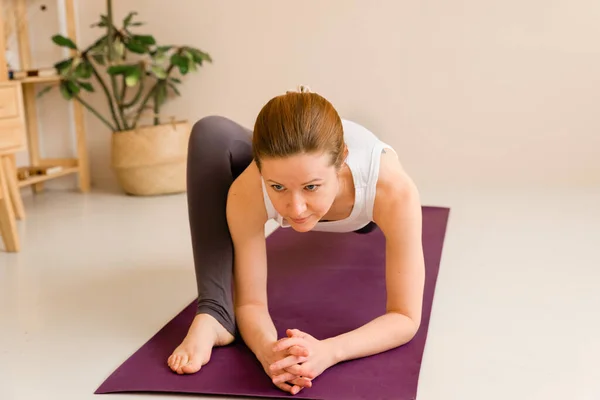 Spor kıyafetli atletik bir kadın evde, oturma odasında spor egzersizleri yapıyor. Spor ve eğlence konsepti