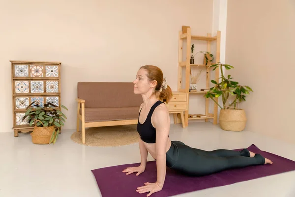Spor elbiseli hoş bir kadın evde dinlenirken yoga yapıyor, sağlık konsepti.