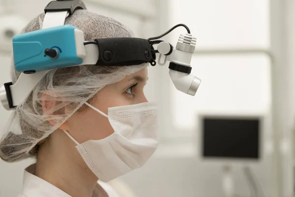 Beyaz önlüklü ve maskeli bir kadın KBB doktoru bir ENT hastanesinin modern ofisinde, yakın plan..