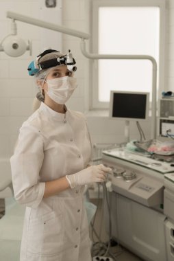 Beyaz önlüklü ve maskeli kadın bir ENT doktoru bir ENT hastanesinin modern ofisinde dikey fotoğrafında..