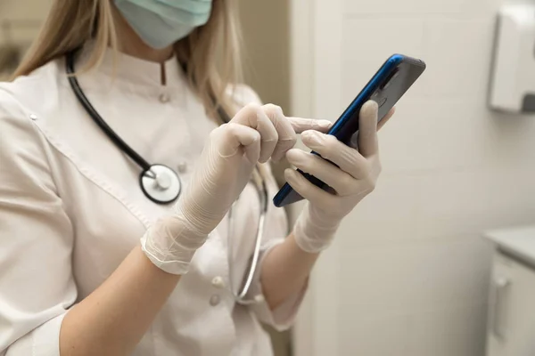 Tıbbi teknoloji konsepti. Hastanenin modern ofisinde cep telefonu ve steteskopla çalışan bir doktor.