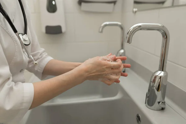 Cropped image of woman doctor washing hands, cleanliness concept.