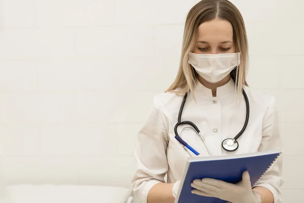 Tıbbi belge dolduran kadın doktor. Steteskoplu genç bir kadın doktor hastaya reçete yazıyor. Hastanedeki panoda kalem yazma tarifi olan kadın doktor..