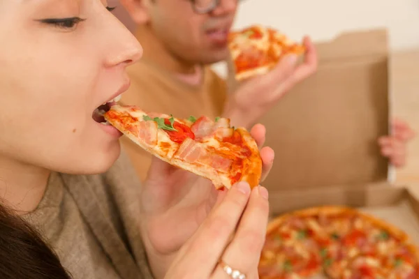 Genç erkek ve kadın çift evde dizüstü bilgisayarla pizza yiyorlar, yakın plan.