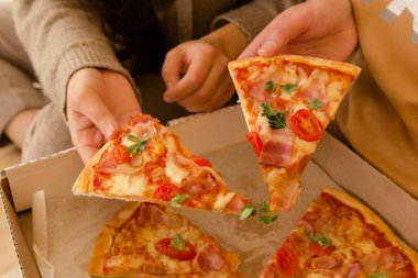 Yemek yemek. İnsanların ellerinin biberli pizza dilimlerini yakın plan çekimleri. Birkaç arkadaş birlikte pizza yiyorlar. Fast food, arkadaşlık, yaşam tarzı. Öğrenciler