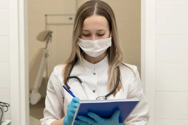 Tıbbi belge dolduran kadın doktor. Steteskoplu genç bir kadın doktor hastaya reçete yazıyor. Hastanedeki panoda kalem yazma tarifi olan kadın doktor..