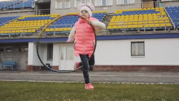 Активная маленькая девочка делает гимнастические упражнения с красочным обручем — стоковое видео