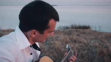 Sahilde gitar çalan yalnız bir adam.