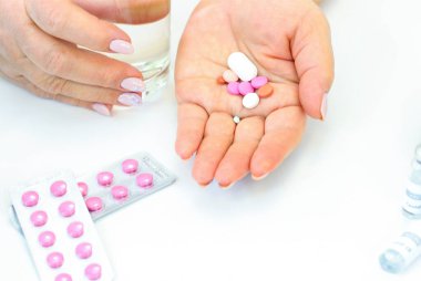 Bir kadın hap içer ve bir bardak su içer.