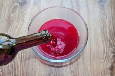 Sıcaktan uzak tut, zorla ve sık. Bir kase içkiye kırmızı şarap dök..