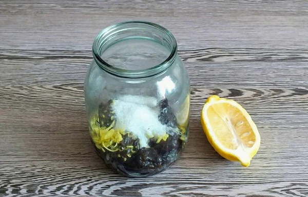 Take a liter glass container. Put squeezed prunes, zest and juice of half a lemon, a tablespoon of sugar into it.