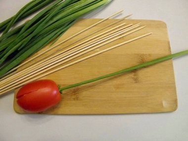 Sapları yap. Bunu yapmak için, yeşil soğanları (tüyler) bir peçeteyle yıkayıp kurutun. Bambu şişini içine sok. Keskin uçlu bir uçla, sapı çiçeğin kafasına sapla. İlk lale hazır..