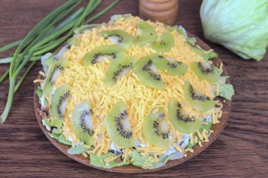 Rendelenmiş sarıyı bir sonraki katmana dök. Yumurtanın sarısına kivi dilimleri koy. Salata hazır! Kivi dilimli alışılmadık et salatası tarifi. Böyle bir salata, şenlik masasının süsü olacak ve sizi bu leziz lezzetiyle memnun edecek. Dene bakalım.